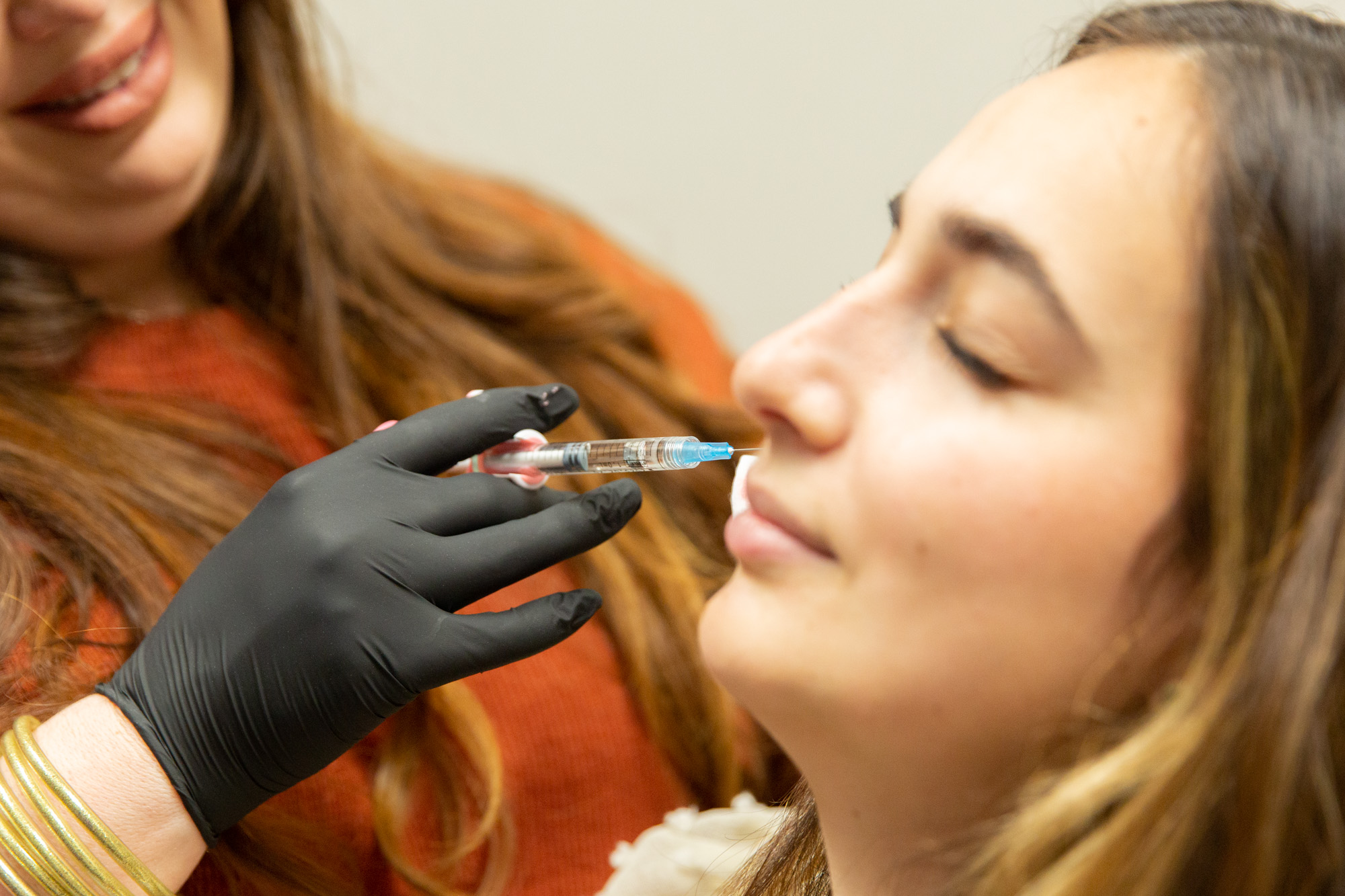 Marcos Medical provider injects dermal fillers into female client's right cheek.