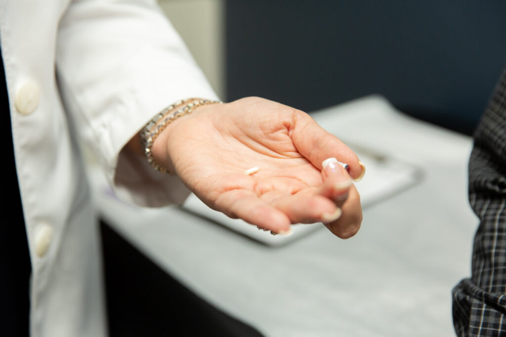 Marcos Medical provider's hand with a hormone replacement therapy pellet in palm.