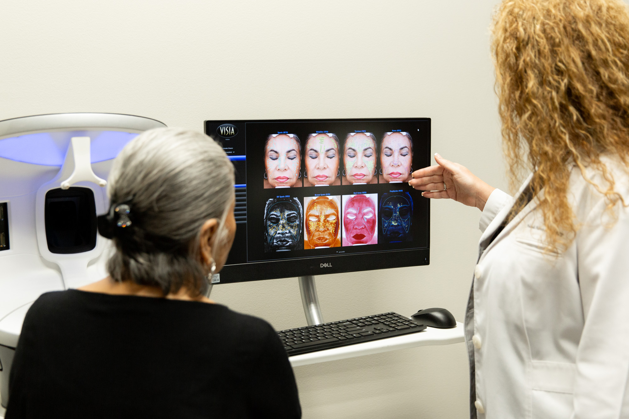 Dr. Marcos shows a patient the results of their VISIA face scan on a computer. The faces of the doctor and patient are not visible.