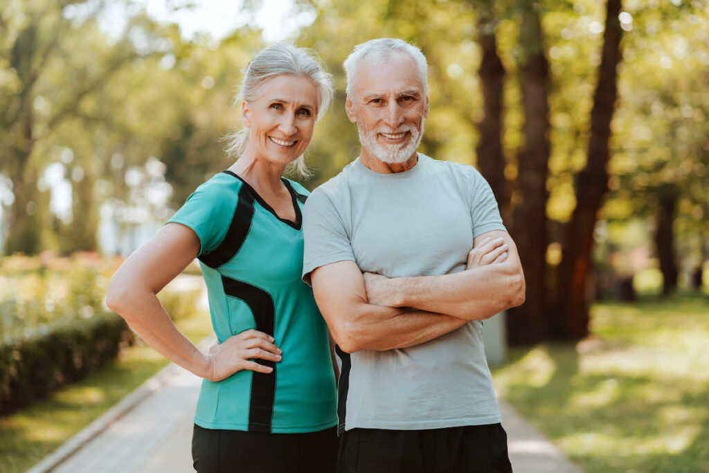 Happy, smiling senior couple wearing sportswear standing with arms crossed in the park posing after having body sculpting in San Antonio