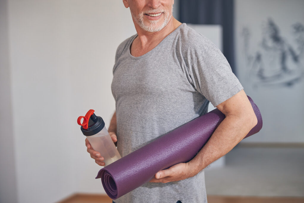 Cropped photo of a bearded muscular male with a happy smile standing at a gym after talking with his TRT Doctor in San Antonio.