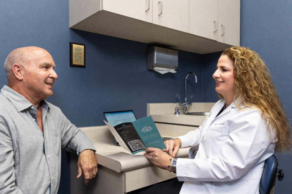 Patient who has lived a healthy life discusses body contouring options like Emsculpt in San Antonio with his medical provider during a consultation